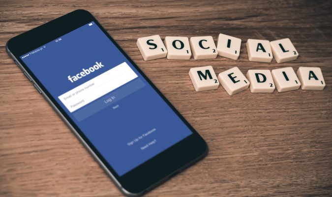Fotografia di uno smartphone e scritta "social network" fatta con tasselli scarabeo