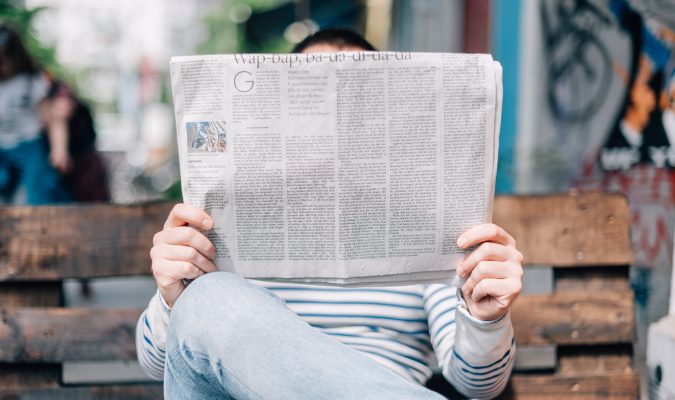 Fotografia di un uomo seduto che legge il giornale