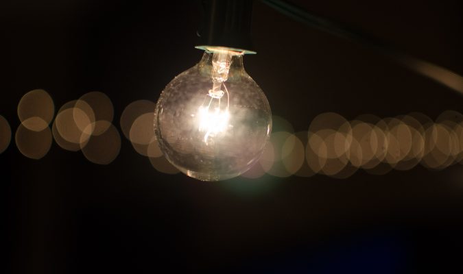 Fotografia di una lampadina accesa in un contesto di buio