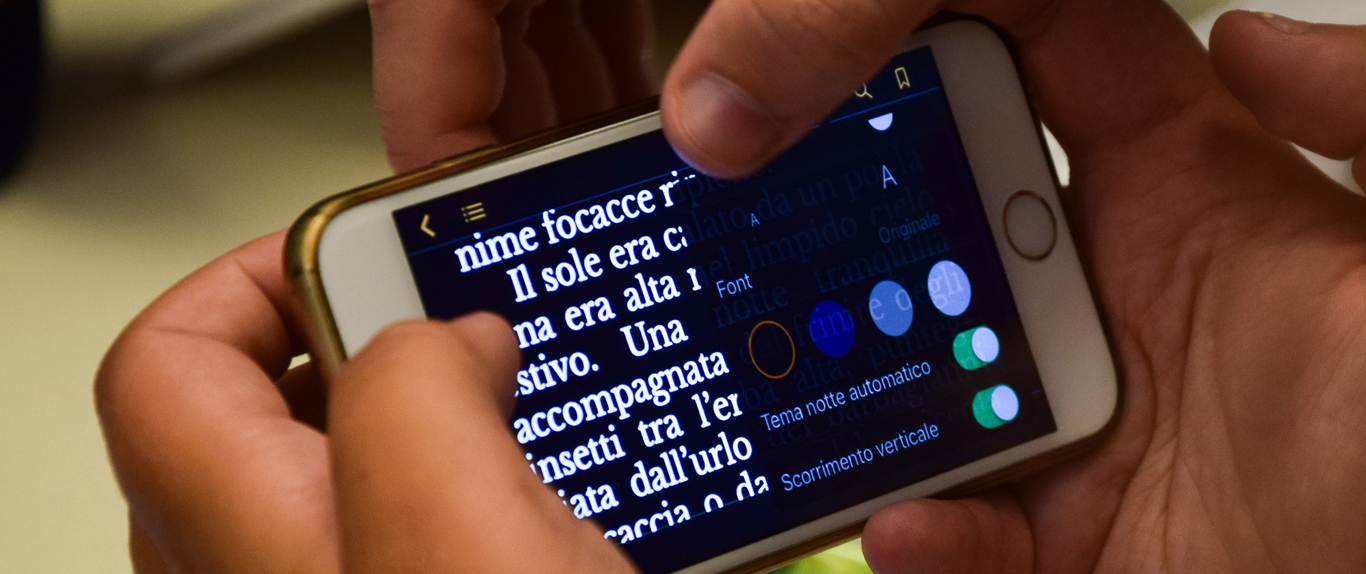 Fotografia di mani che usano smartphone. In primo piano sullo schermo un testo e le opzioni per personalizzare la visualizzazione