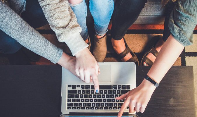 Fotografia di persone sedute davanti a un computer, mentre indicano lo schermo