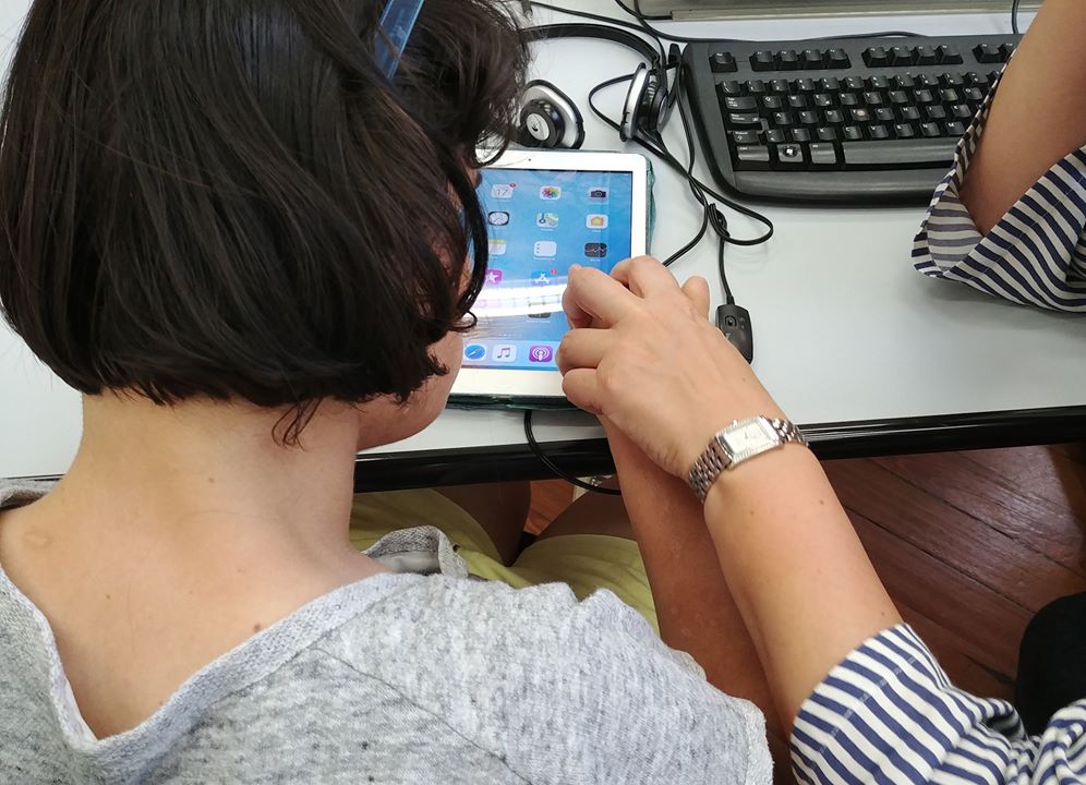 Fotografia di una ragazza di spalle mentre utilizza un device aiutata da un formatore LIA