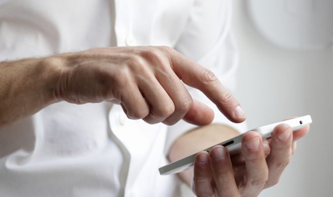 Fotografia del mezzo busto di un uomo che utilizza uno smartphone