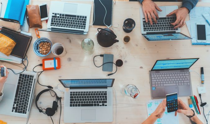 Fotografia di tavolo con laptop e smartphone e persone al lavoro