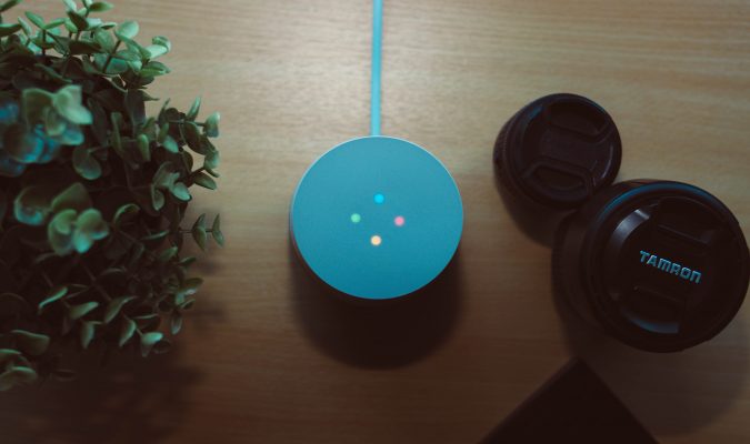 Fotografia dall'alto di un tavolo su cui ci sono un Google home e degli obiettivi