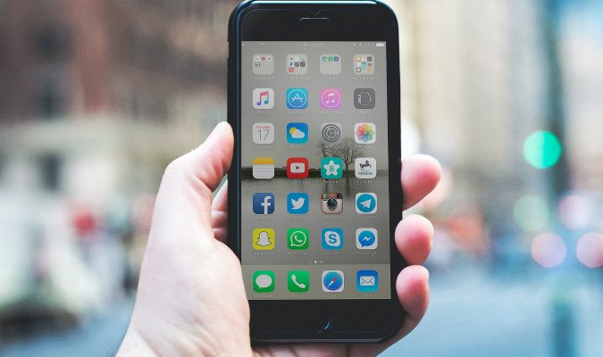 Fotografia di una mano che regge uno smartphone con schermo acceso
