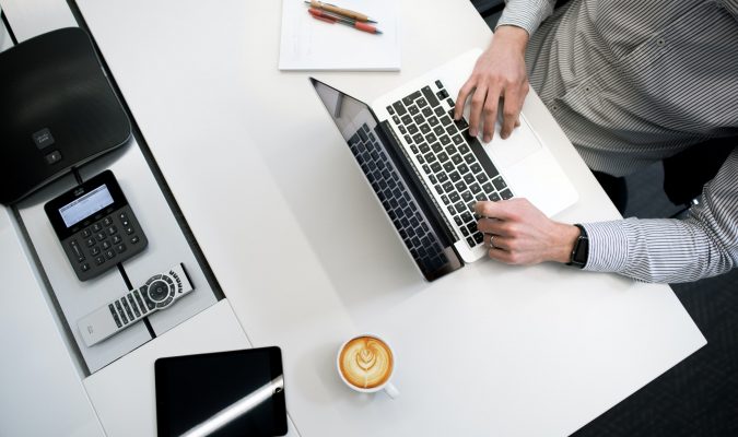 Photograph of a person at a desk with devices and materials for taking notes