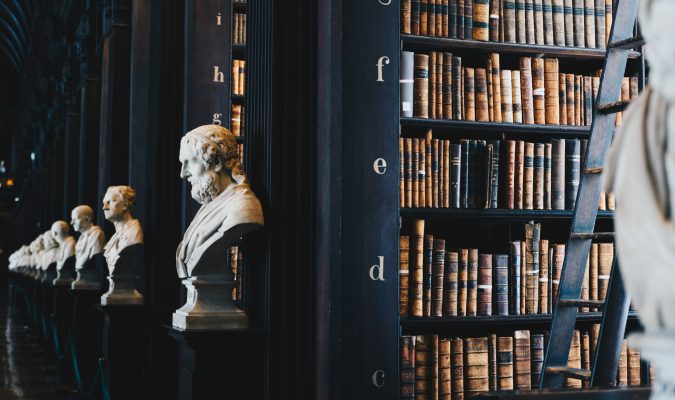 photograph of a bookshelf in a library, a statue bust in the foreground