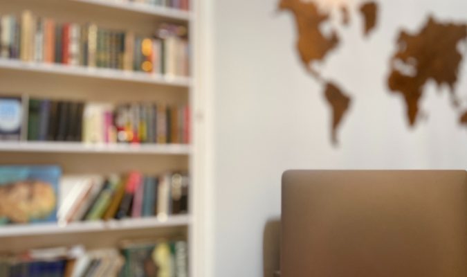 Fotografia di un portatile e sullo sfondo una libreria