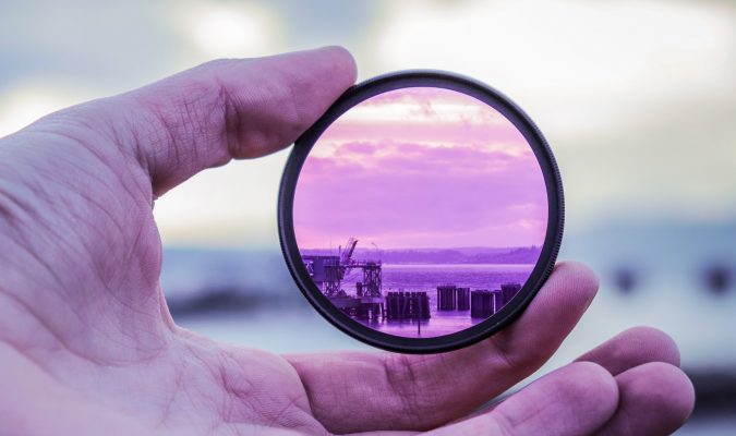 Fotografia di una mano che regge una lente di ingrandimento