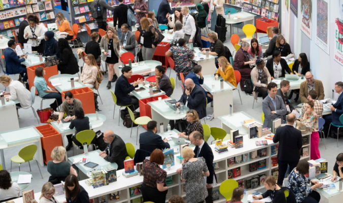 Fotografia di una hall con persone sedute a dei tavolini durante la London fair