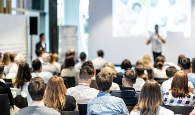 Foto di una sala piena di persone durante una conferenza