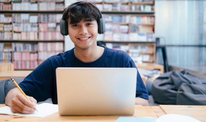 Fotografia di un ragazzo che sta utilizzando un portatile con delle auricolari
